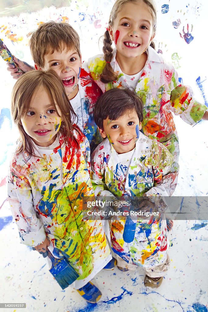 Messy Hispanic children covered in paint