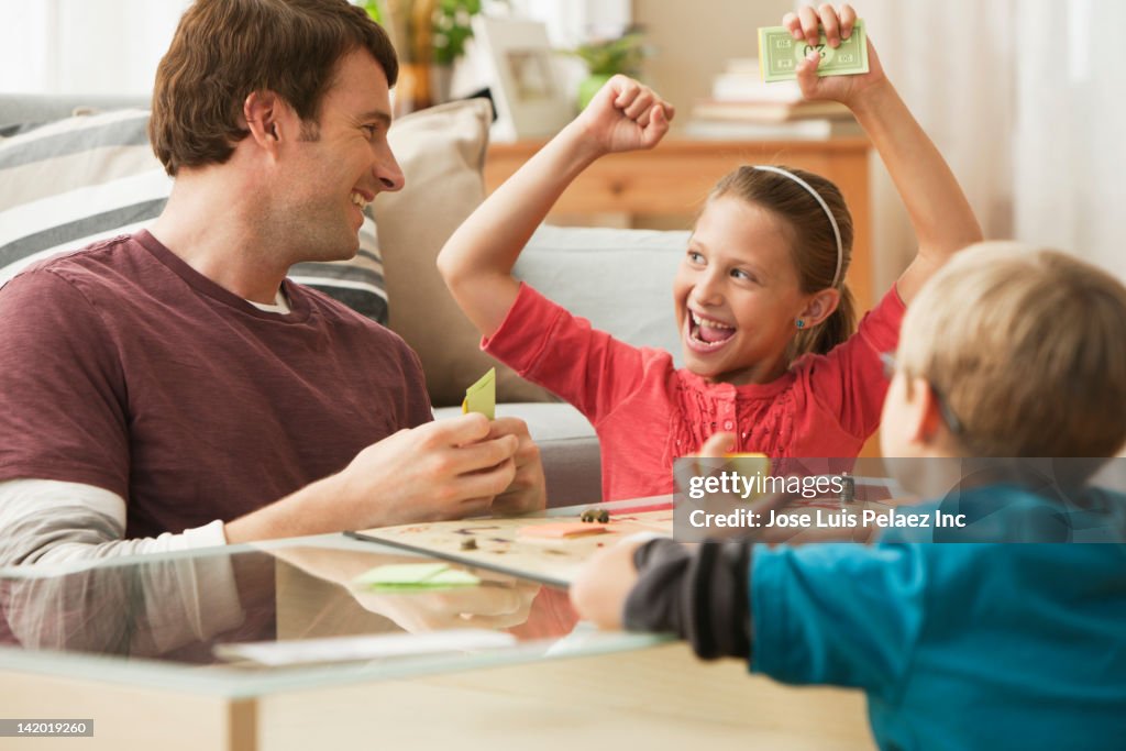 Caucasian father and children playing board game