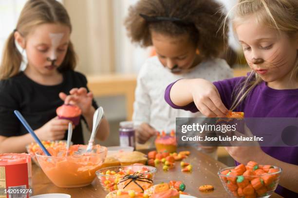 girls in halloween costumes decorating cupcakes - candy corn imagens e fotografias de stock