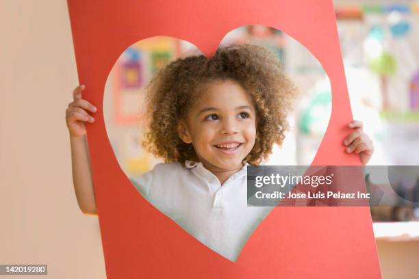 grinning mixed race boy looking through heart-shaped hole - valentines african american 個照片及圖片檔