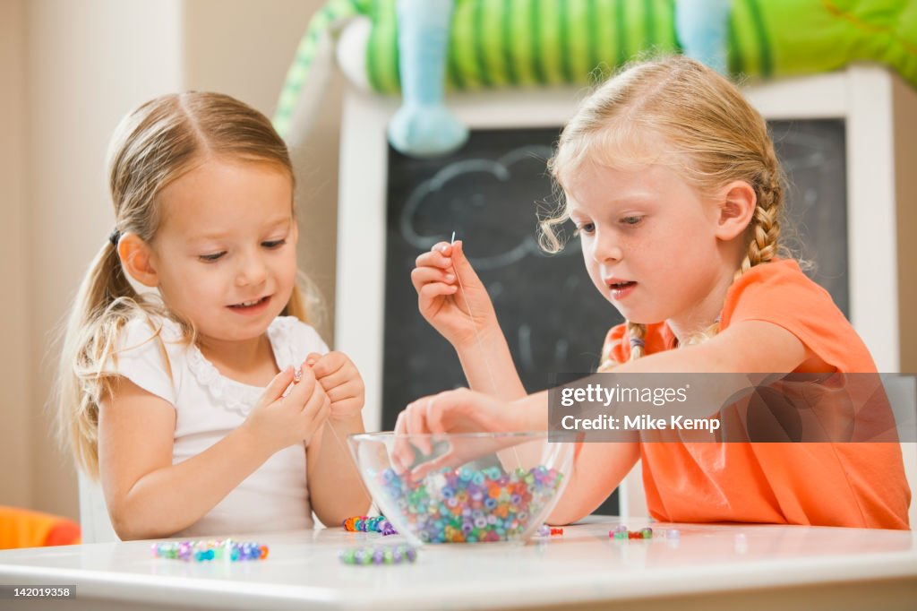 Caucasian sisters playing with beads