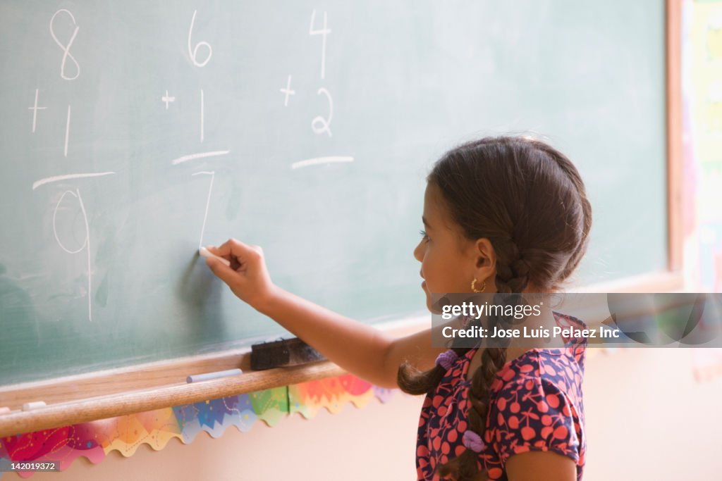 Hispanic girl doing math on blackboard