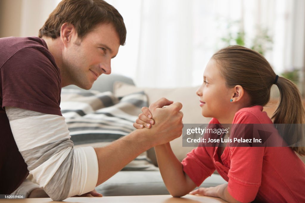 Caucasian father and daughter arm wrestling