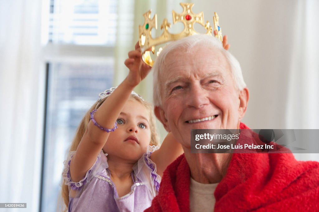 Caucasian girl putting crown on grandfather's head