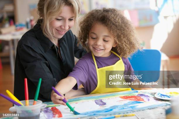 teacher watching student painting picture - child art stockfoto's en -beelden