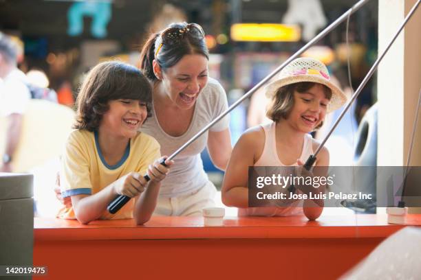 Hispanic Family Playing Arcade Game In Amusement Park, Foto de stock
