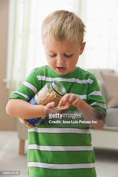 caucasian boy eating peanuts - banknoten stockfoto's en -beelden
