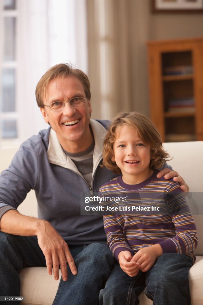 Caucasian man sitting on sofa with son