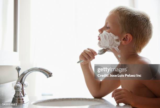 caucasian boy pretending to shave his face - crema de afeitar fotografías e imágenes de stock