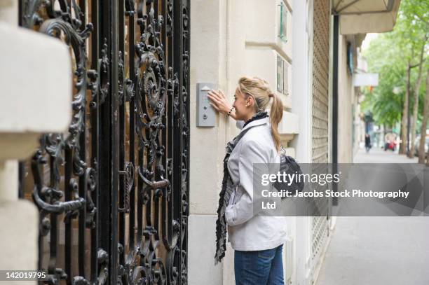 hispanic woman pressing buzzer on city street - citofono foto e immagini stock