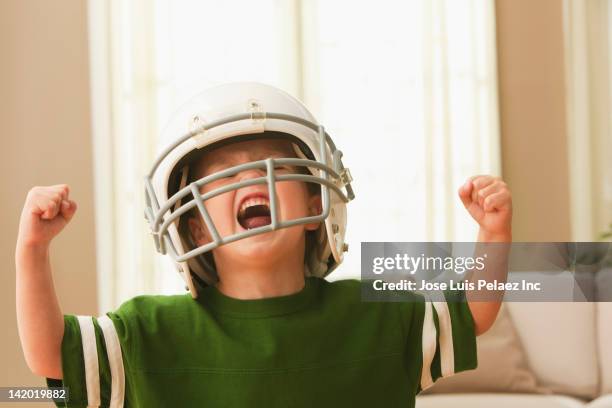 cheering caucasian boy in football uniform - protective sportswear stock-fotos und bilder