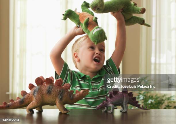 caucasian boy playing with toy dinosaurs - child picking up toys stock pictures, royalty-free photos & images