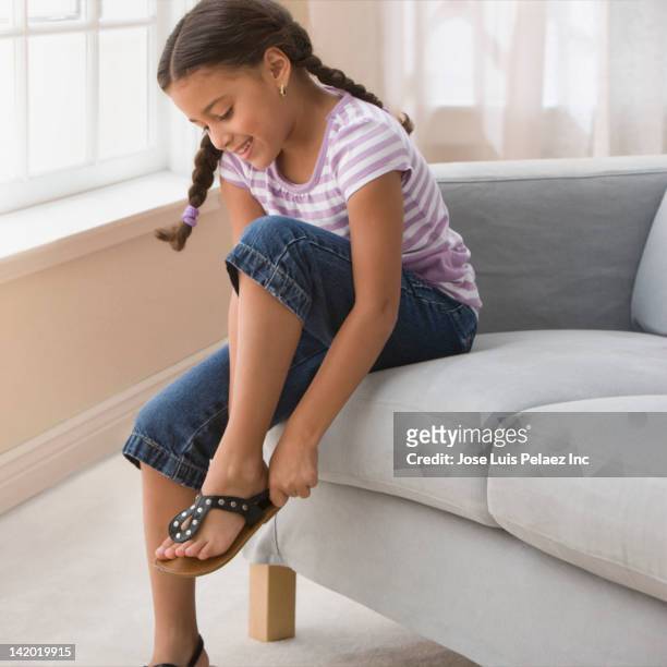 hispanic girl putting on sandals - girls wearing sandals stock-fotos und bilder