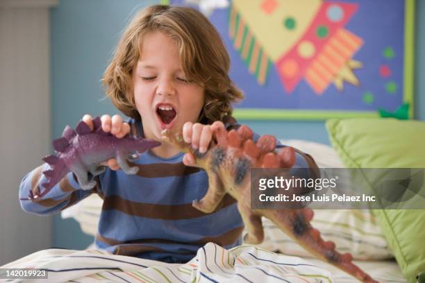 caucasian boy playing with dinosaurs on bed - furious 7 foto e immagini stock