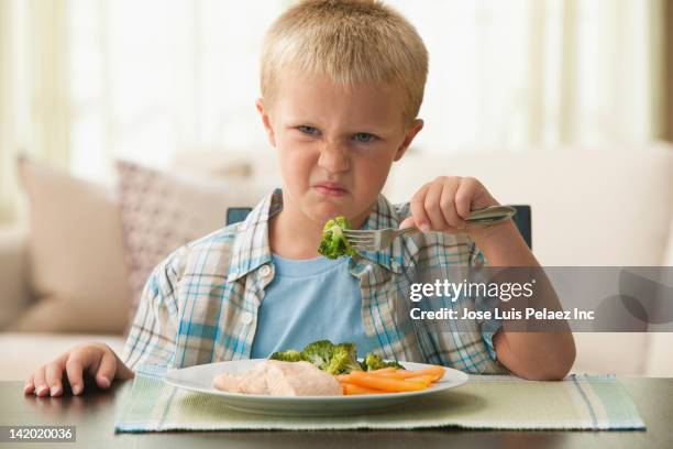 unhappy caucasian boy eating vegetables - frowning stock pictures, royalty-free photos & images