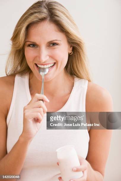 smiling caucasian woman eating yogurt - blond women happy eating stock pictures, royalty-free photos & images