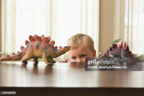caucasian boy playing with toy dinosaurs - toy dinosaur stock pictures, royalty-free photos & images