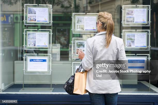 hispanic woman looking at real estate sign - panneau à vendre photos et images de collection