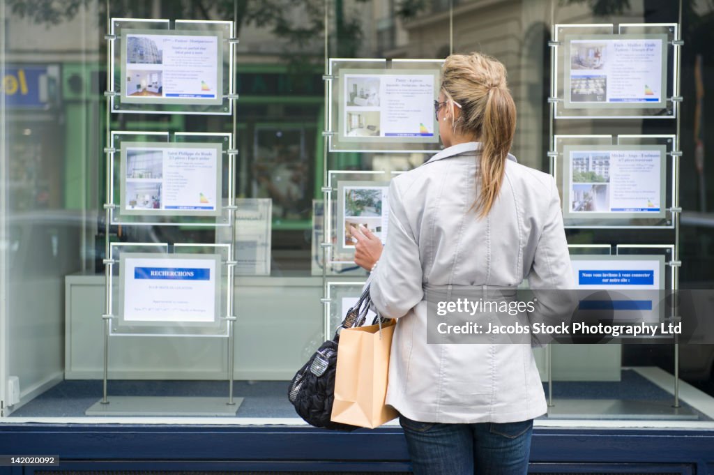Hispanic woman looking at real estate sign
