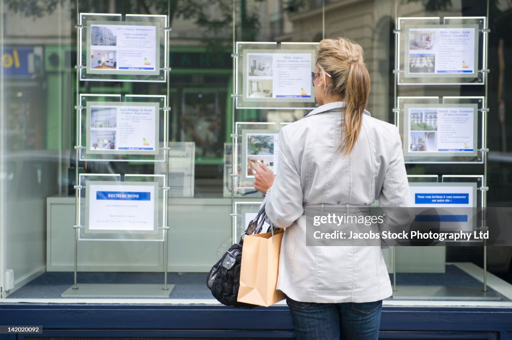 Hispanic woman looking at real estate sign