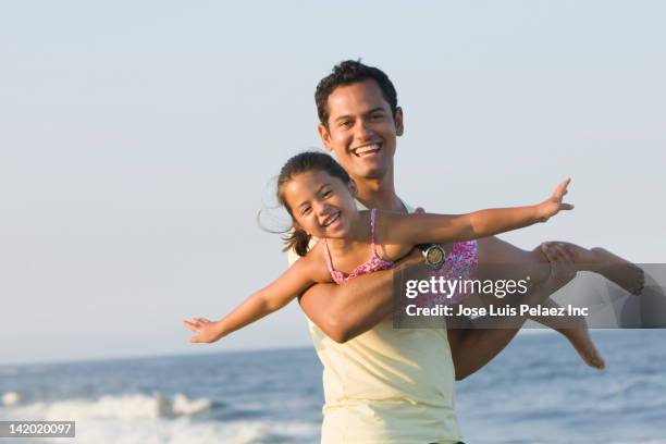 father swinging daughter on beach - hot latino girl imagens e fotografias de stock