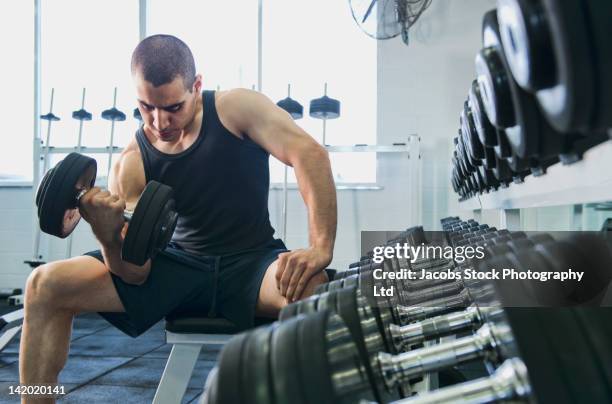 middle eastern man exercising with dumbbells - bíceps fotografías e imágenes de stock