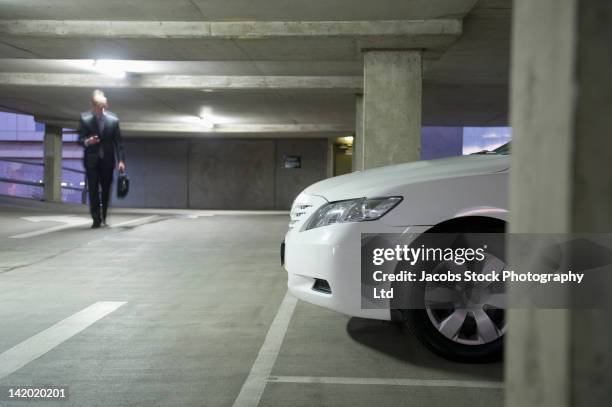 caucasian businessman walking in parking garage - parking lot stock pictures, royalty-free photos & images