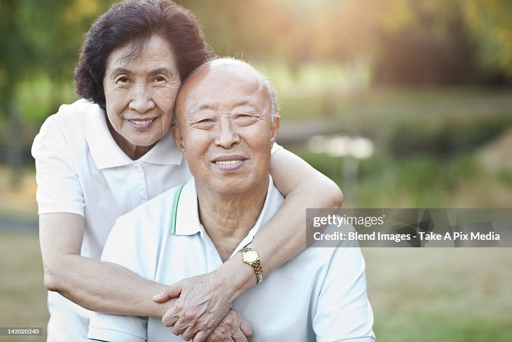 Smiling senior Chinese couple hugging