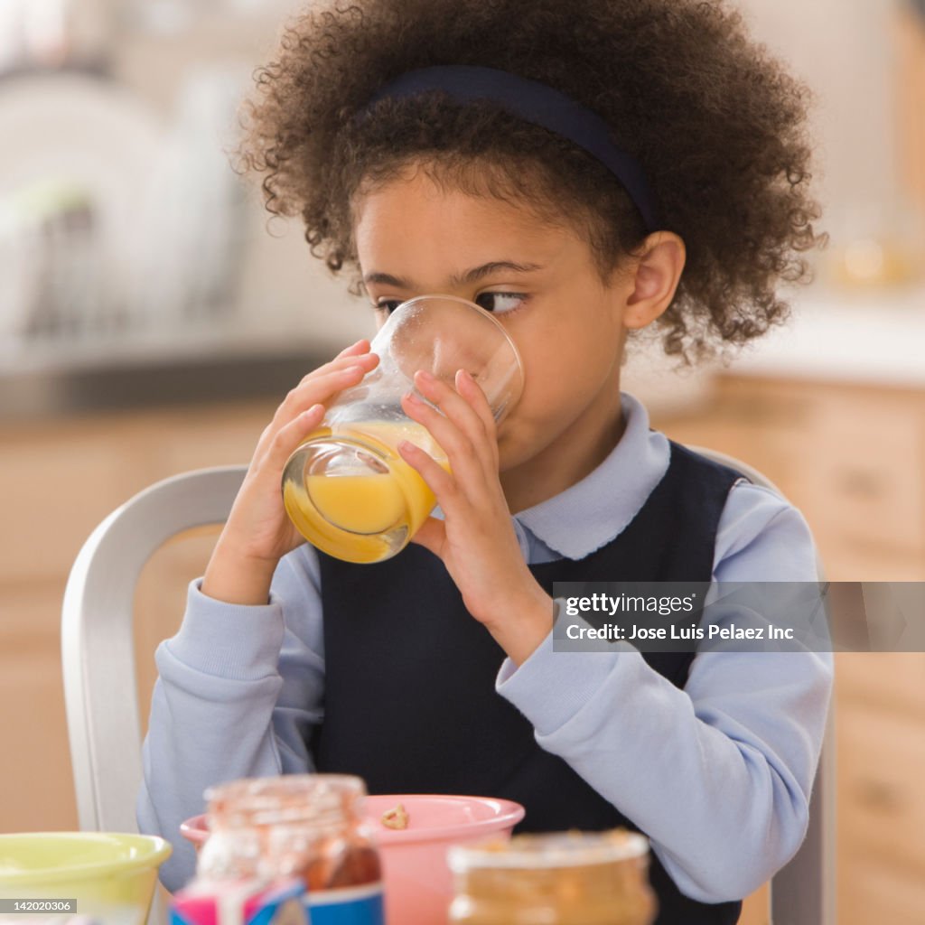 Mixed race girl drinking orange juice