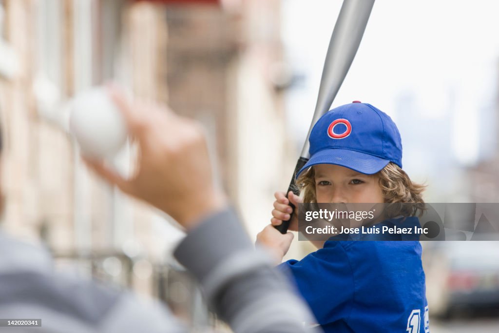 Caucasian boy playing baseball with father
