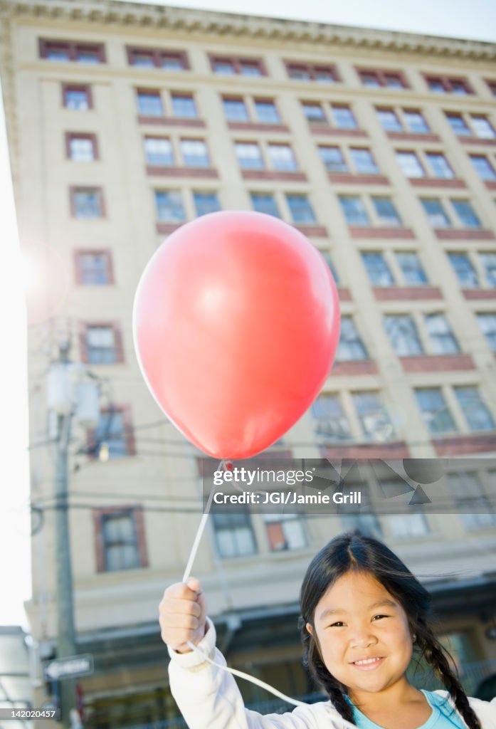 Korean girl holding red balloon outdoors