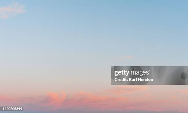 a view of pink fluffy clouds at sunset - himmel stock-fotos und bilder