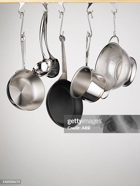 pots and pans hanging from hooks - pan keukengereedschap stockfoto's en -beelden