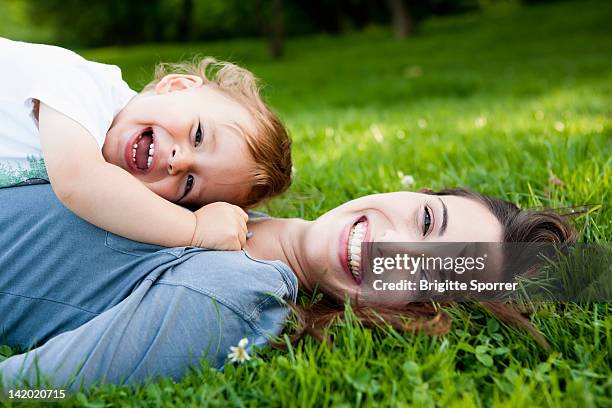 mother holding toddler in park - baby lachen natur stock-fotos und bilder