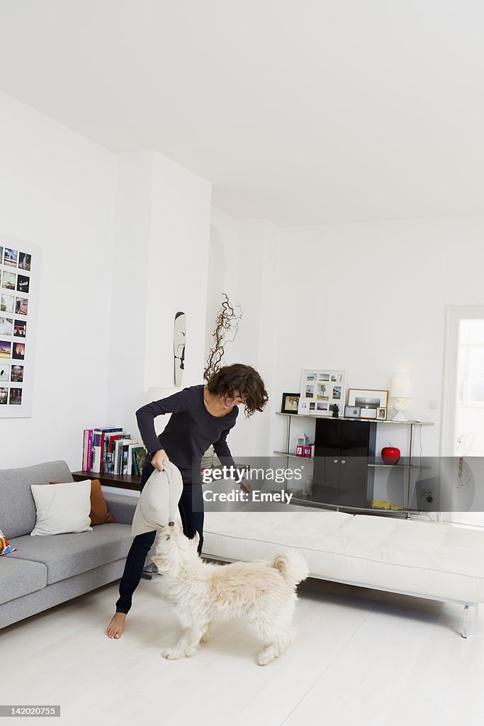 Woman playing with dog in living room