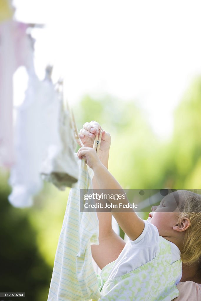 Caucasian mother and baby hanging laundry on clothes line