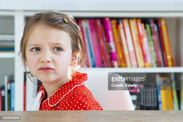 frowning girl sitting at table - förödmjukelse bildbanksfoton och bilder