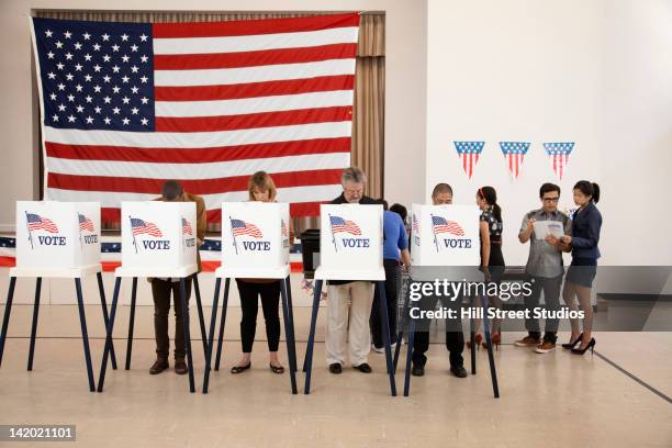 people voting in polling place - votar fotografías e imágenes de stock