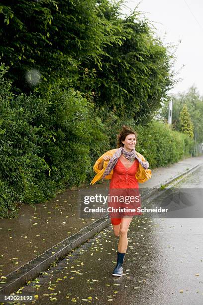 smiling woman running in rain - wet stock pictures, royalty-free photos & images