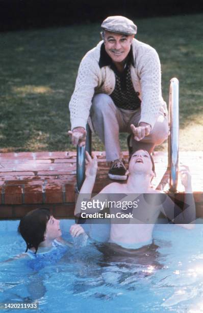 American actor & dancer Gene Kelly crouches beside his swimming pool and plays with two of his children, Bridget and Timothy, at their Beverly Hills...
