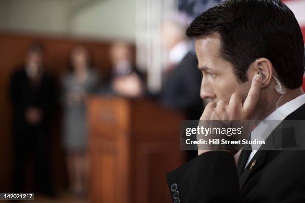 security guard listening to earpiece at public speech - hermosa beach stock-fotos und bilder