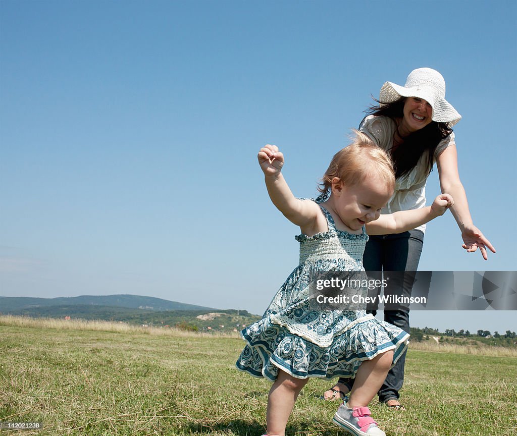 Mother and daughter walking in field
