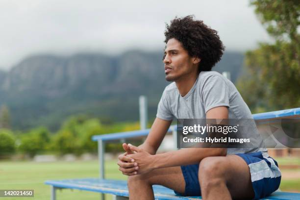 man sitting on bleachers in park - college athlete stock pictures, royalty-free photos & images