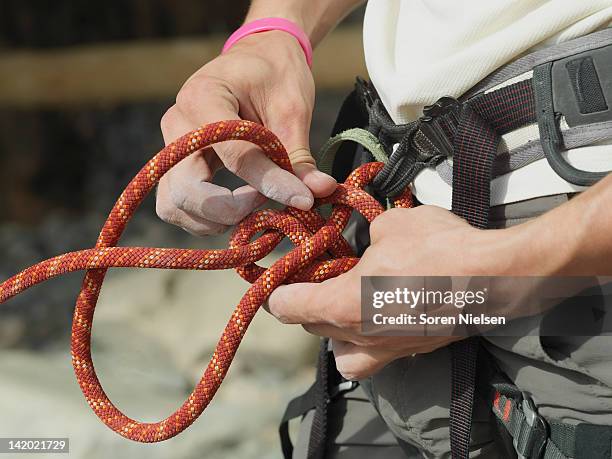 close up of rock climber tying knot - safety harness stockfoto's en -beelden