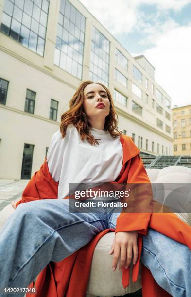 portrait of a beautiful young woman in the city - rode spijkerbroek stockfoto's en -beelden
