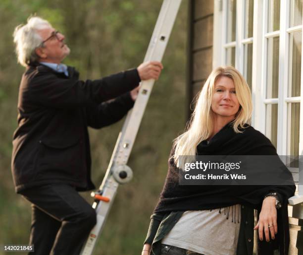 woman smiling as husband climbs ladder - ladder leaning stock pictures, royalty-free photos & images