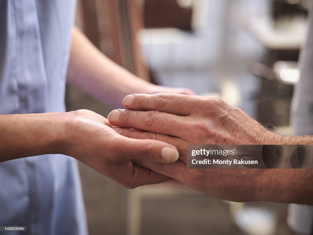 Carer holding hand of senior man