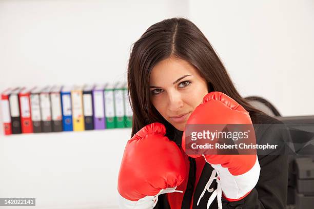 businesswoman wearing boxing gloves - combat sport fotografías e imágenes de stock
