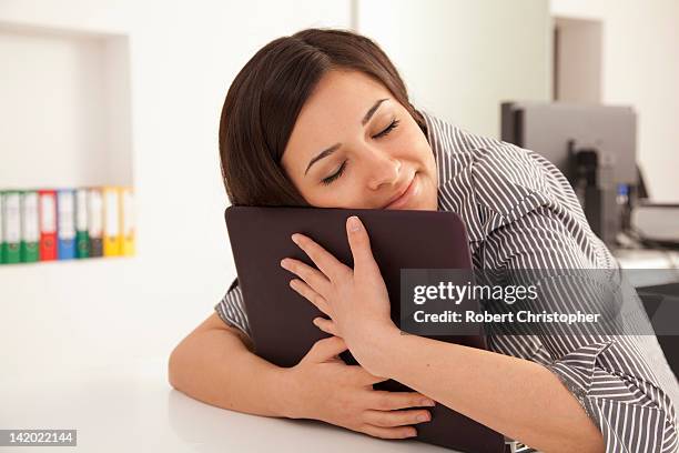 Businesswoman hugging computer in office