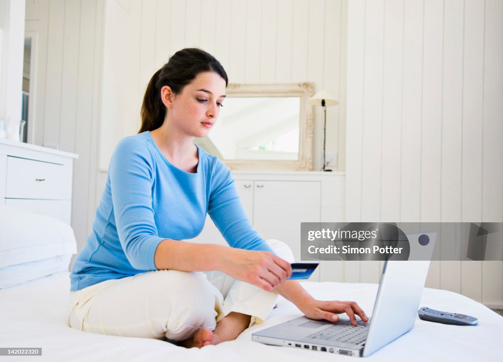 Woman shopping online on bed
